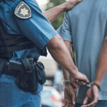 Stop, handcuffs and hands of police man with criminal in city for justice, crime or corruption. Illegal, arrest and law enforcement officer with suspect, thief or gangster for jail, robbery or fail